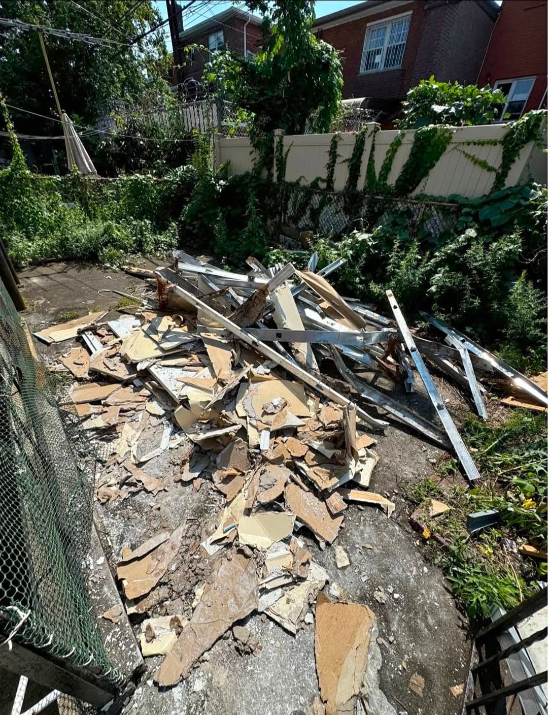 Backyard covered with demolition rubble including drywall, metal studs, and construction waste
