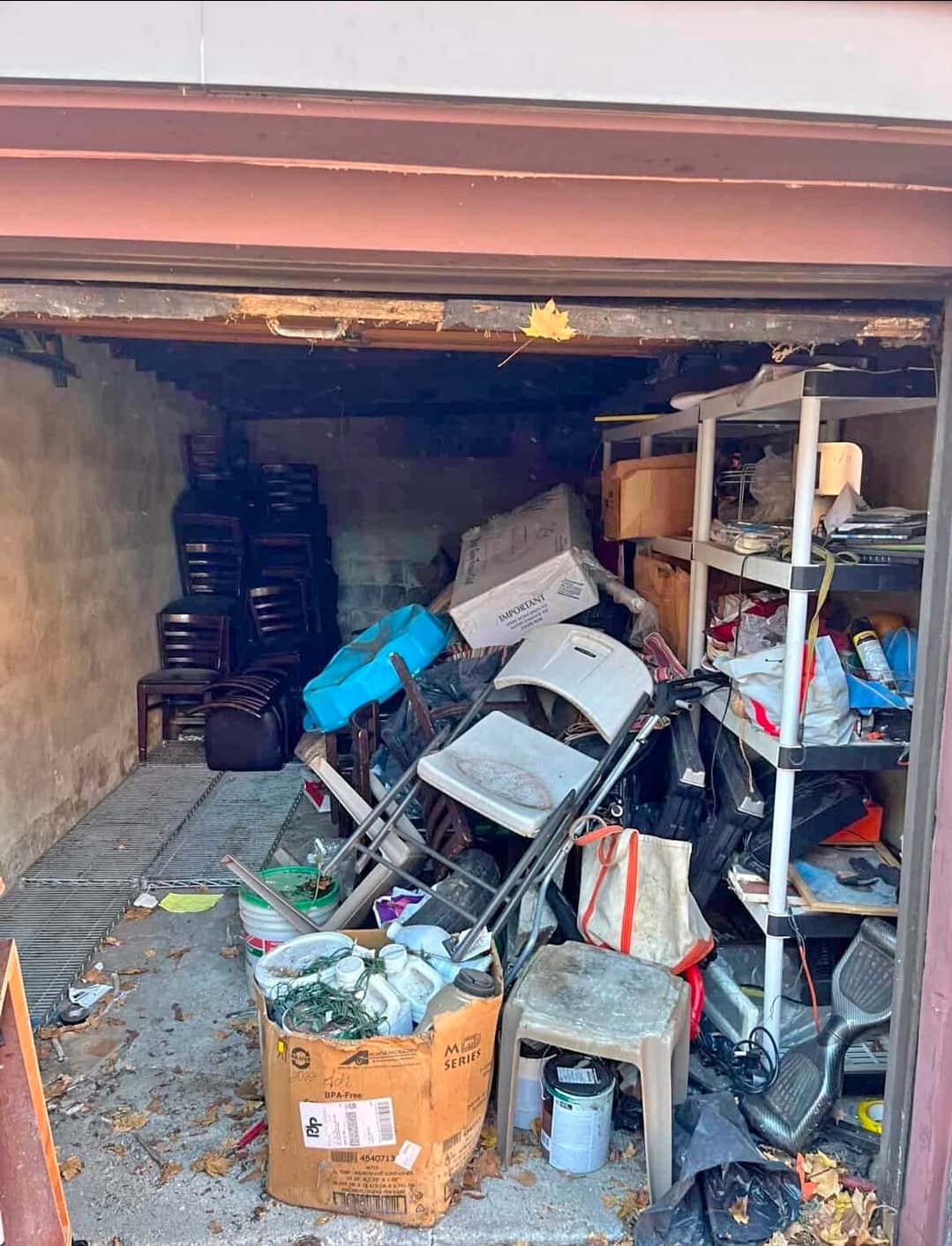 Cluttered garage full of stacked chairs, boxes, buckets, and miscellaneous items